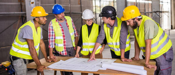 istock Group of construction engineers reviewing plans 645502240