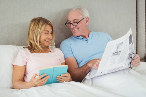istock Senior couple on bed reading newspaper and book 645505932