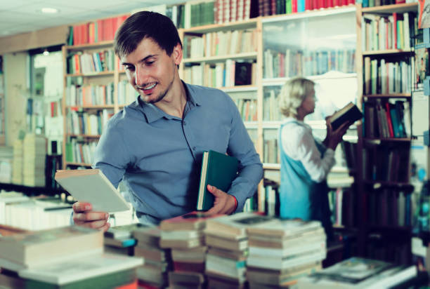 istock Young smiling man customer choosing new book 645518518