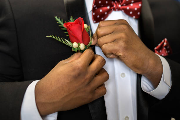 Pinning boutonniere to lapel Teen pins his rose boutonniere to formal suit getting dressed and ready for prom. prom stock pictures, royalty-free photos & images