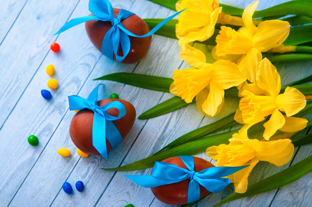 Easter background with decorative Easter eggs, narcissus and willow tree branch. Copy space, top view