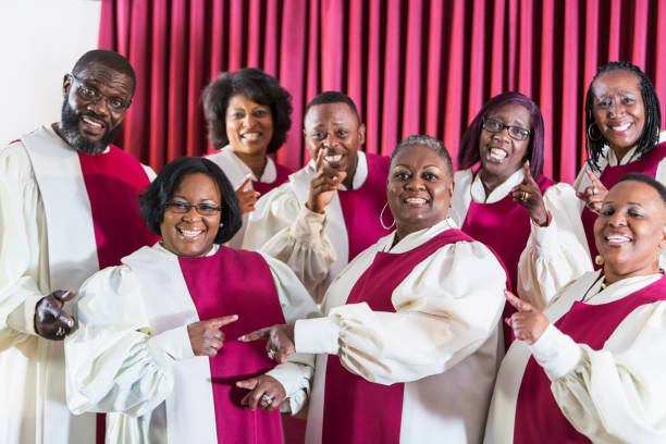 Mature black women and men singing in church choir A group of mature African American women and men wearing robes, singing in a church choir. gospel stock pictures, royalty-free photos & images