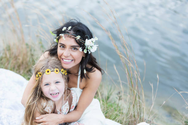 istock Boho-chic young woman and child sitting by lake 645583764