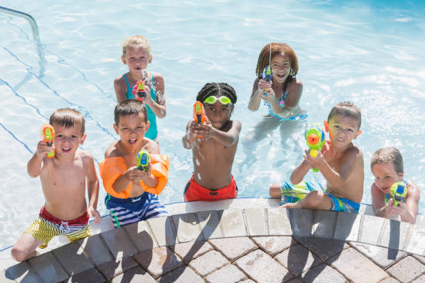 istock Multi-ethnic group of children in pool with squirt guns 645600668