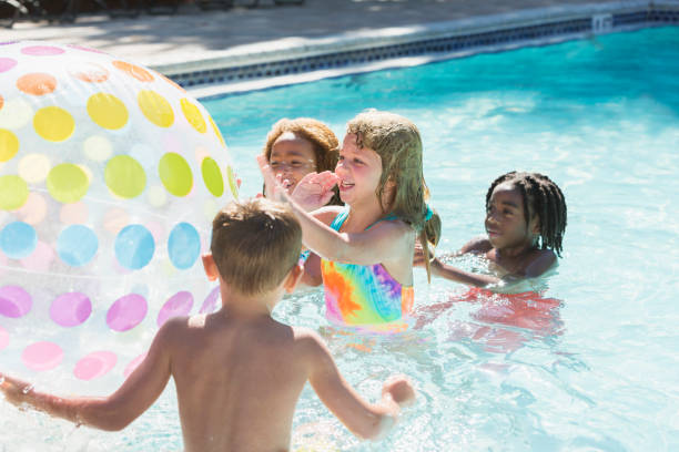 enfants multiethniques avec ballon de plage géant dans la piscine - beach ball swimming pool ball child photos et images de collection