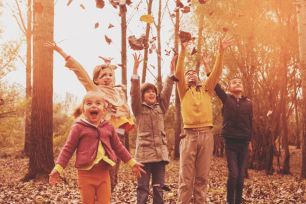 istock Group of children throwing leaves up. 645606902