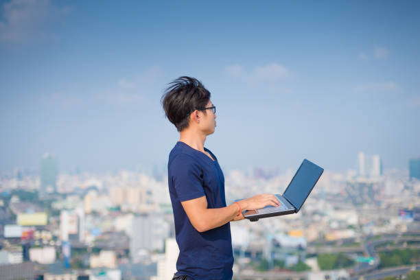 istock Young business man using laptop and digital tablet cityscape background 645616066