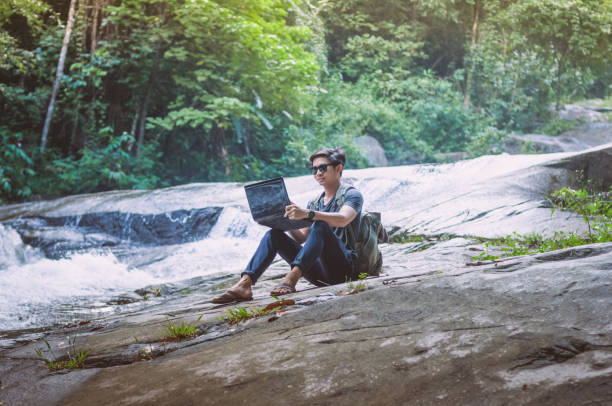 istock Hiker with backpack and laptop and phone at  waterfall  the forest. 645619390