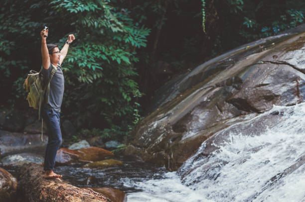 istock Hiker with backpack and laptop and phone at  waterfall  the forest. 645619394
