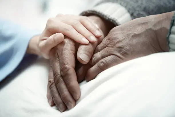 Photo of Hand of woman touching senior man in clinic