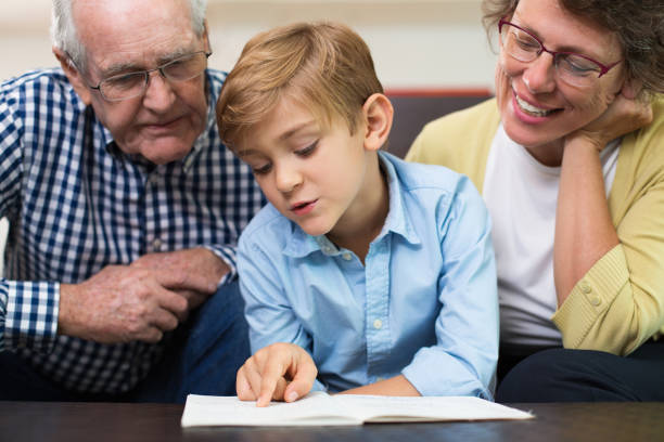 istock Diligent schoolboy reading book with grandparents 645631602