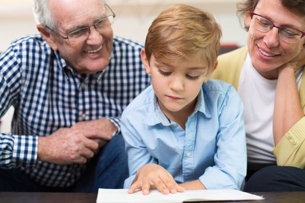 istock Serious little boy reading book with grandparents 645631676