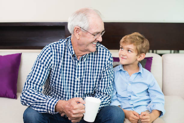 istock Smiling senior man sitting on sofa with grandson 645631712
