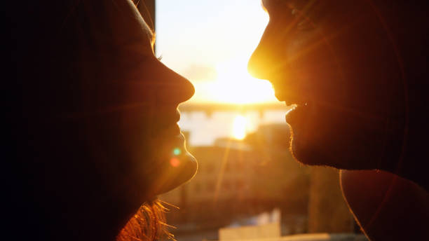 istock Romantic young couple looking each other on a sunset with sun shining bright behind them on a horizon. 645632228