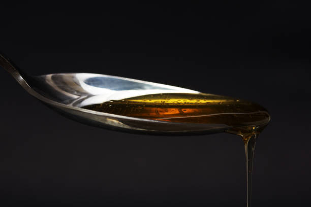 istock Honey pouring from spoon against a dark background 645643274