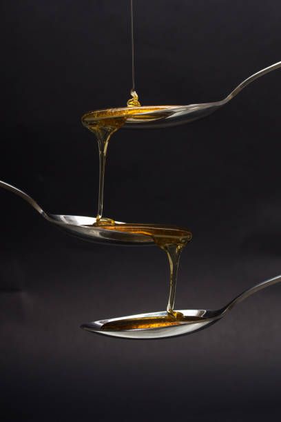istock Honey pouring from spoon against a dark background 645643288