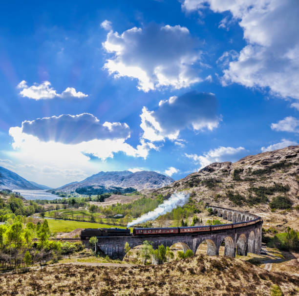 viadotto ferroviario di glenfinnan in scozia con il treno a vapore giacobita contro il tramonto sul lago - glenfinnan foto e immagini stock