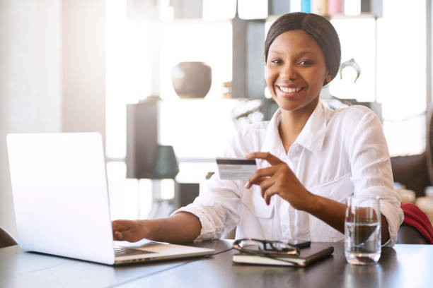 istock Attractive black woman smiling at camera while making online payments 645656566