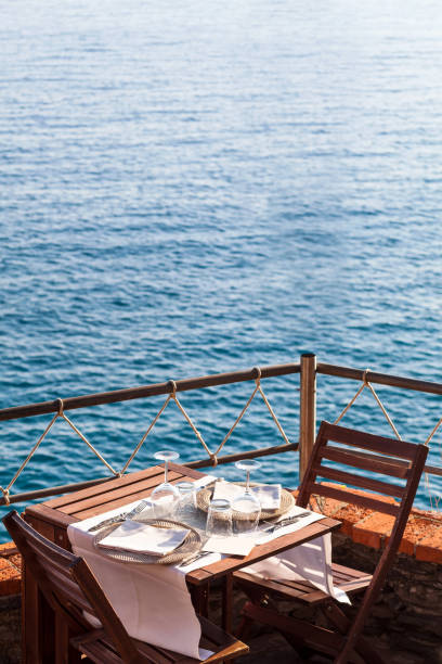 Wooden table with white, dishwater and chairs on ocean in a restaurant in Italy, Europe