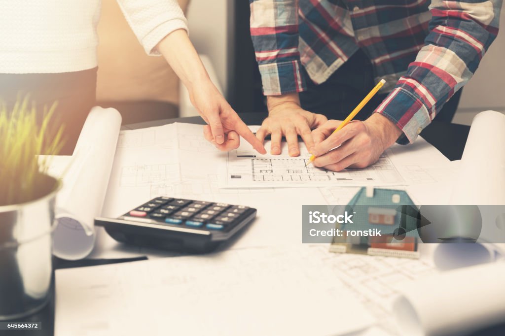 architects working with blueprints on a new house project Building - Activity Stock Photo