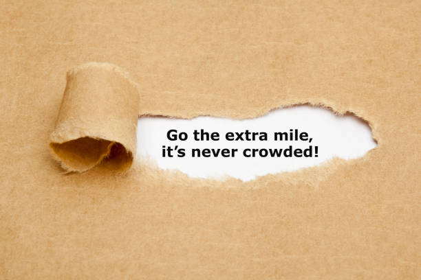 Go The Extra Mile Its Never Crowded Motivational quote Go The Extra Mile It's Never Crowded appearing behind ripped brown paper. never stock pictures, royalty-free photos & images