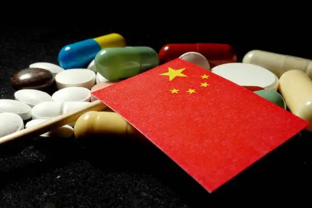 Chinese flag with lot of medical pills isolated on black background