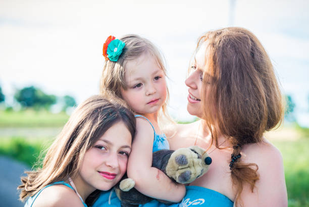 portrait of mother and two daughters. mother looking at daughter