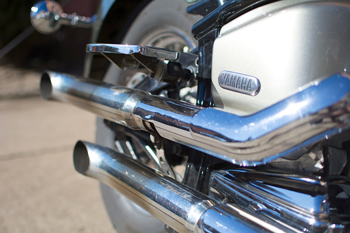 Beautiful exhaust system with three chrome pipes on the side of the historic motorcycle - a sepia toned image