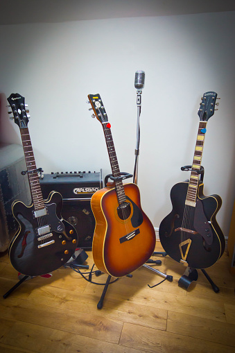 Newcastle-upon Tyne, private house collection of Gretsch and gibson electric and semi acoustic guitars on stands in front of an amplifier with a Shure vintage microphone between them.
