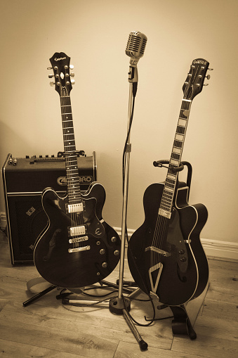 Newcastle-upon Tyne, private house collection of Gretsch and gibson electric and semi acoustic guitars on stands in front of an amplifier with a Shure vintage microphone between them.