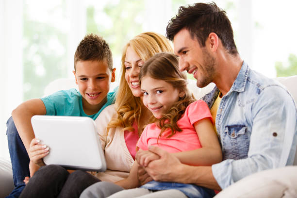 семья, используя ноутбук на дому - two parent family technology mobility men стоковые фото и изображения