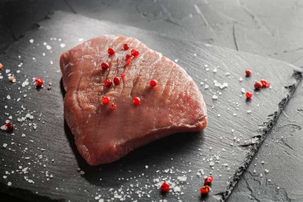 istock raw beef steak with rosemary and peppers on dark stone 645711590