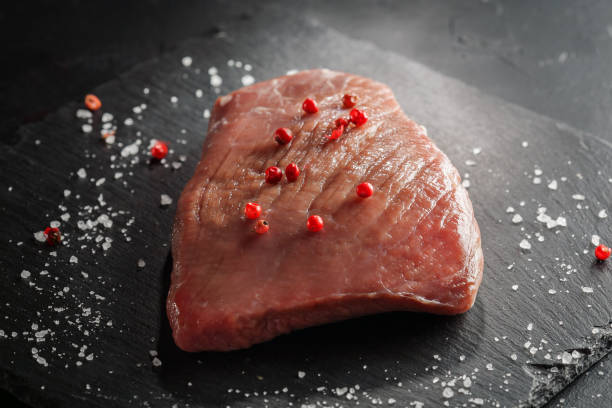istock raw beef steak with rosemary and peppers on dark stone 645711602