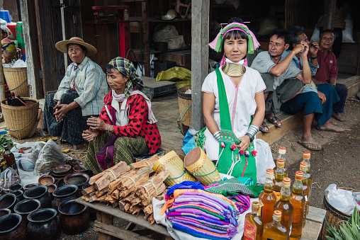 Loikaw, Myanmar - May 25, 2016: Padaung (Karen) long neck woman selling goods in brass rings around neck in traditional clothes on the Demawso market