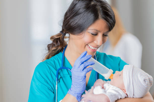 istock Pediatric nurse smiles at infant while giving her a bottle 645720418