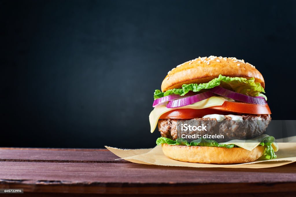 Craft beef burger. Craft beef burger on wooden table isolated on dark blue background. Burger Stock Photo