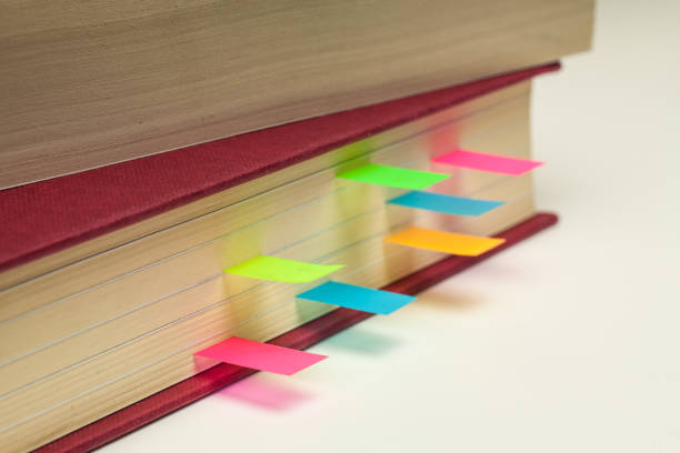 Books marked with colorful sticky notes on a black desk.