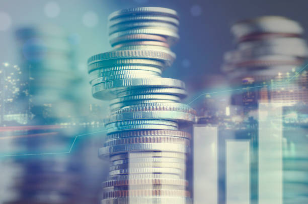 Double exposure of city and graph on rows of coins stock photo