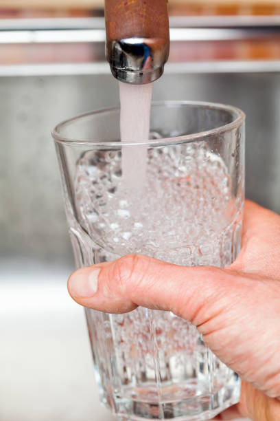 istock Filling up a glass with water from kitchen tap POV 645737656