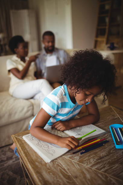 istock Daughter drawing on book while parents using laptop in background 645741480