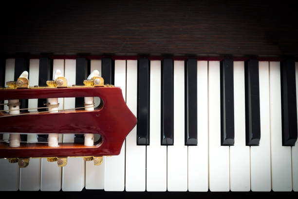 istock Closeup head of guitar on piano keyboard. Top view. 645742128