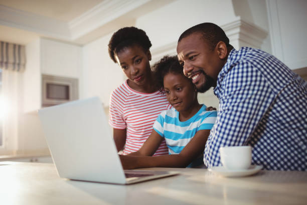 istock Parents and daughter using laptop in kitchen 645748870