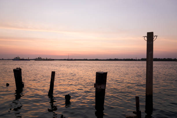 Wooden pier or jetty remains on blue lake sunset and sky reflection water, Thailand.