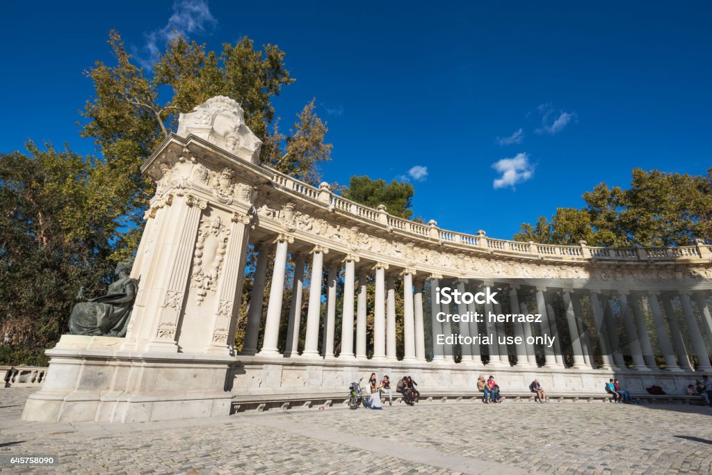 Tourist visiting Alfonso XII monument in Retiro park, Madrid, Spain. Madrid, Spain - November 13, 2016 : Tourist visiting Alfonso XII monument on November 13, 2016 in Retiro park, Madrid, Spain. Architectural Column Stock Photo