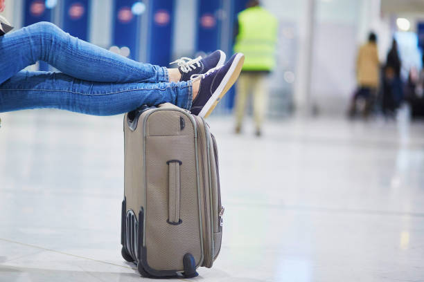 Closeup of woman feet on a suitcase in international airport Closeup of woman feet on a suitcase in international airport. Delayed or canceled flight concept hand luggage stock pictures, royalty-free photos & images