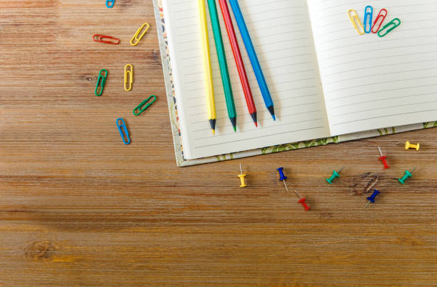 istock creative work place with open note book,pencils and colorful clips .wooden table.space for text.top view. 645768428