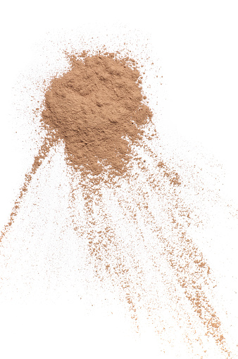 Scattered tan colored facial loose powder isolated on white background. Top view point.
