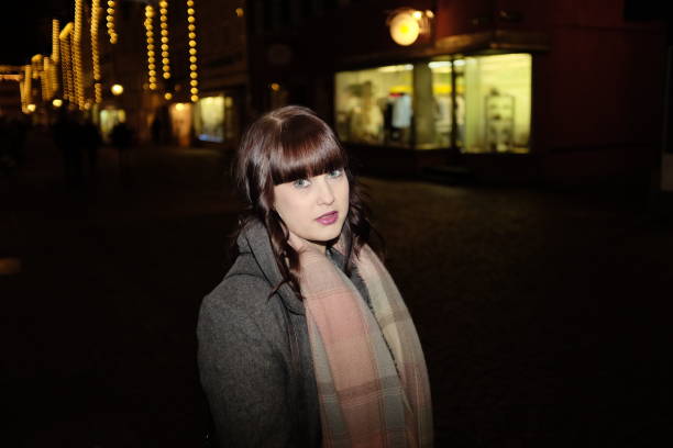 istock Young woman outdoors in town at night 645774336
