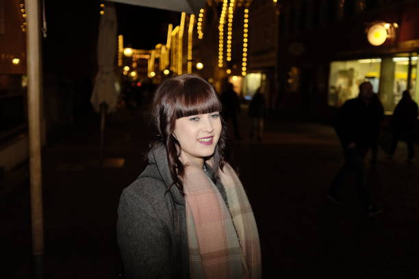 istock Young woman outdoors in town at night 645774344