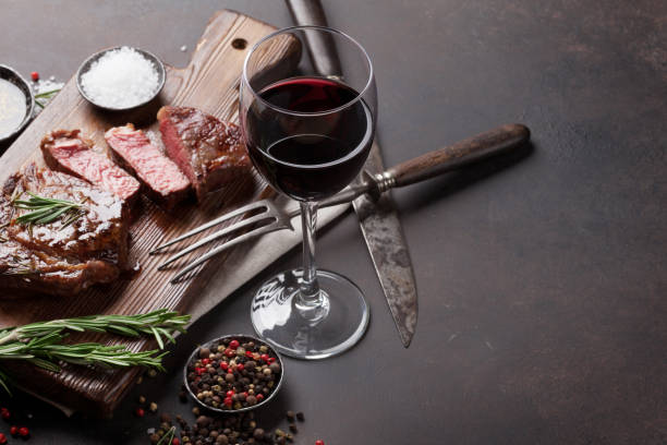 grilled ribeye beef steak with red wine, herbs and spices - wine imagens e fotografias de stock